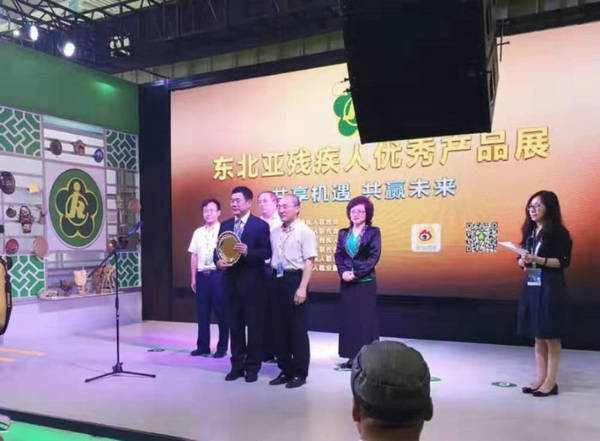 图为省残联向东北亚博览会秘书处捐赠牌匾和残疾人创作的作品